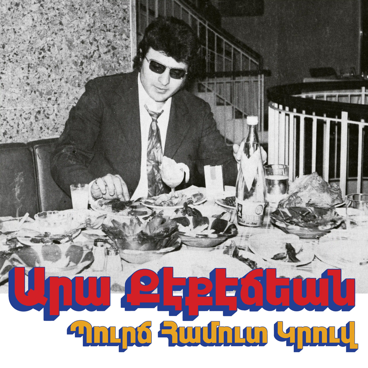 Ara Kekedjian - Bourj Hammoud Groove Vinyl Record
Man in a suit sitting at a table with food and drinks, with text overlay in a different language.