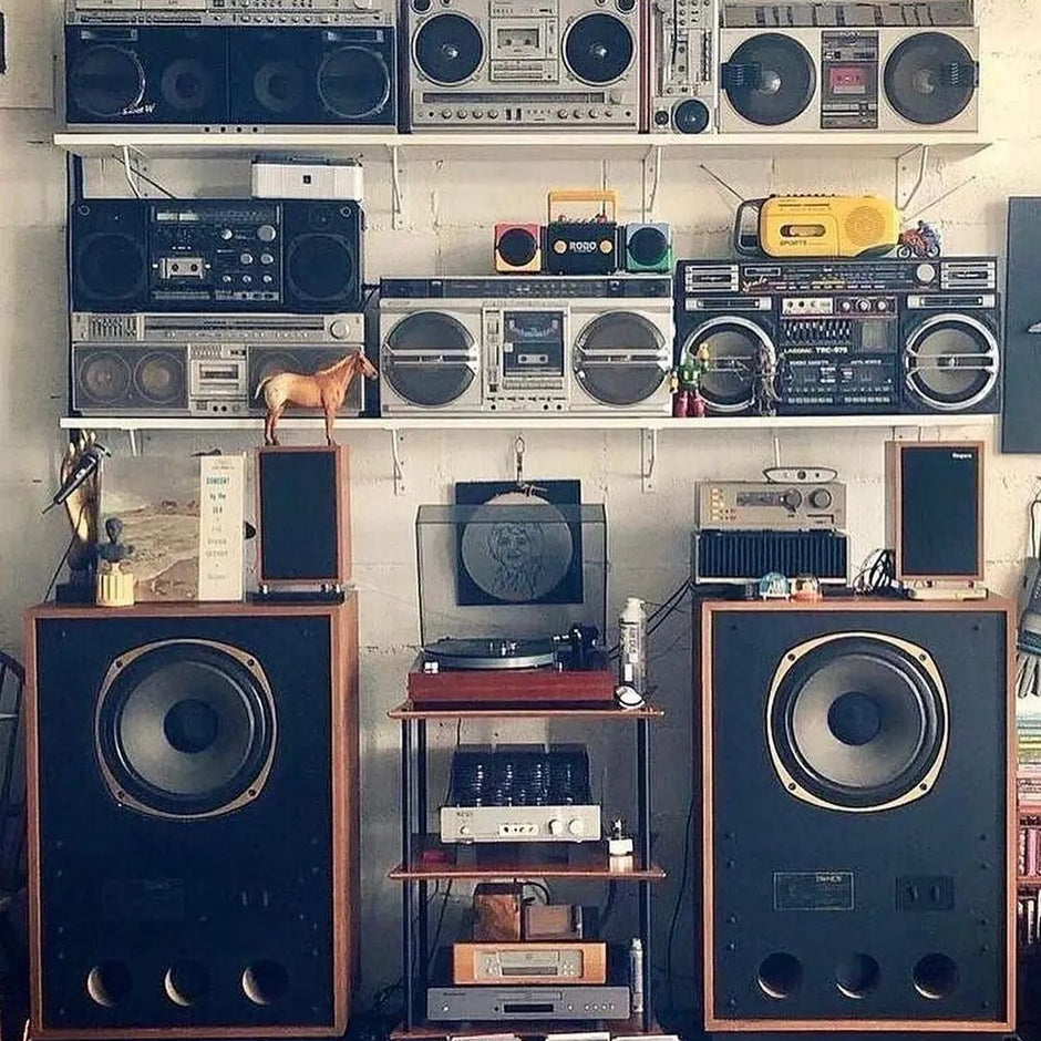 A collection of vintage audio equipment and boomboxes displayed on a brick wall.
