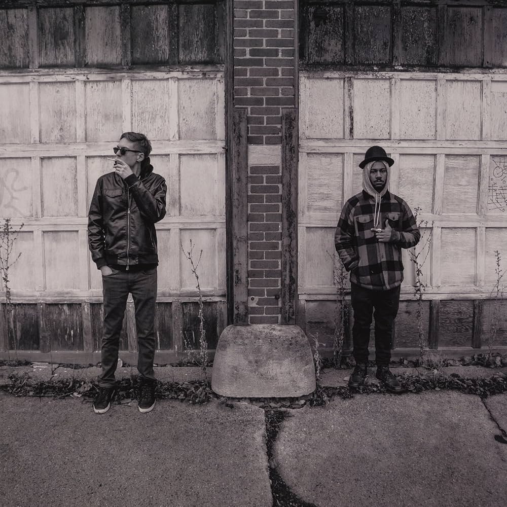 two men standing next to a building